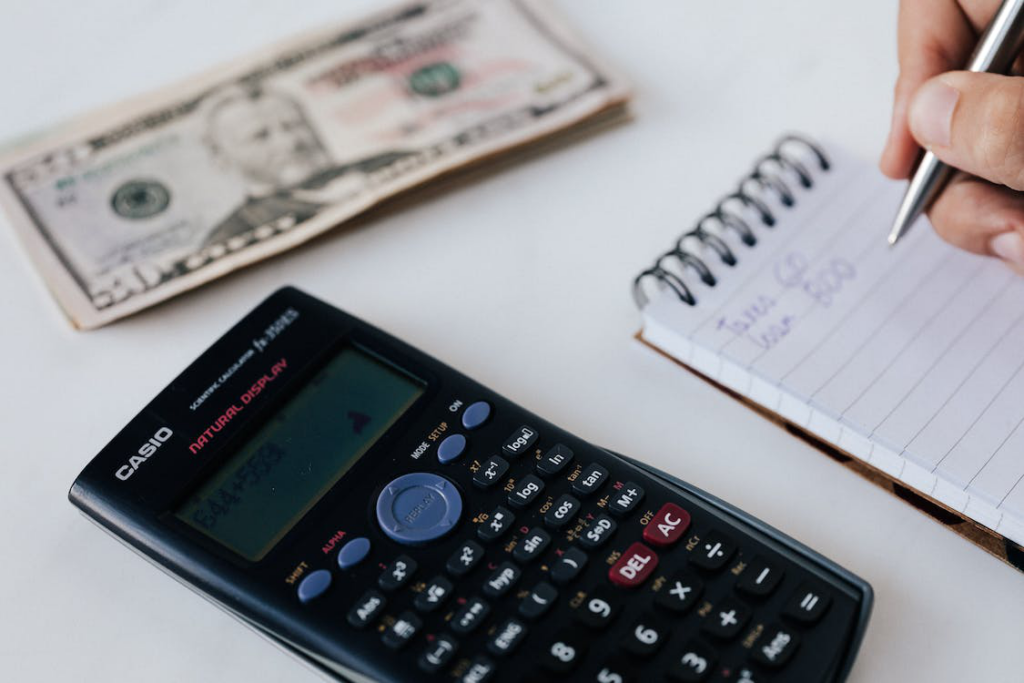 a person counting savings using a notebook and calculator