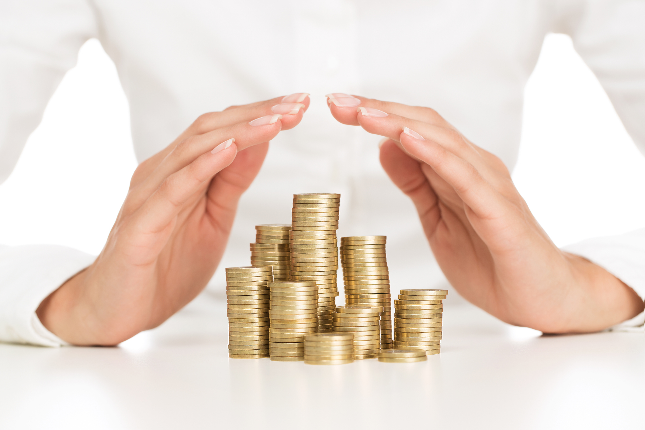 Close up of female hands covering stack of golden coins